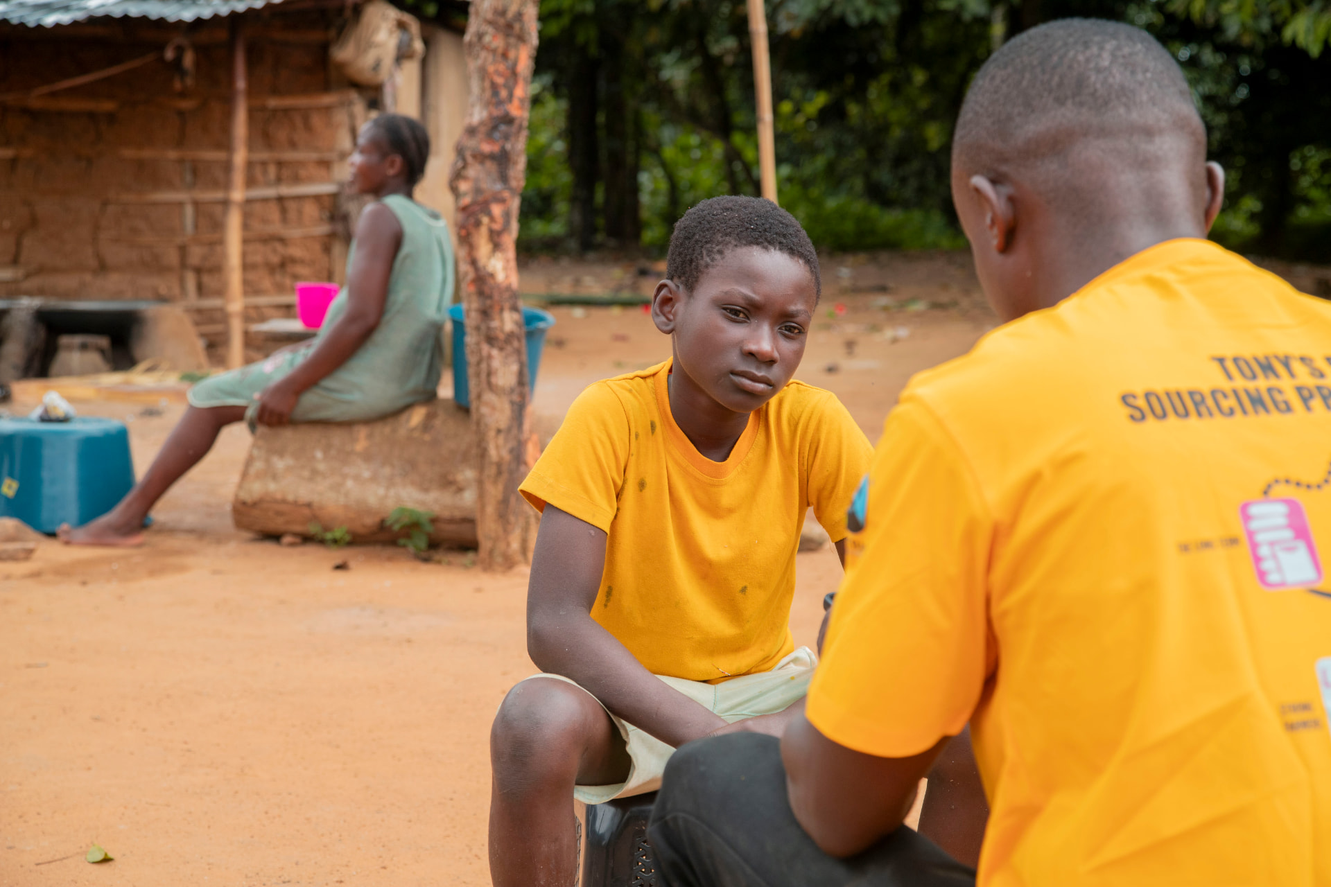 An Asetenapa field officer speaking with a young boy during a household child-labour monitoring visit